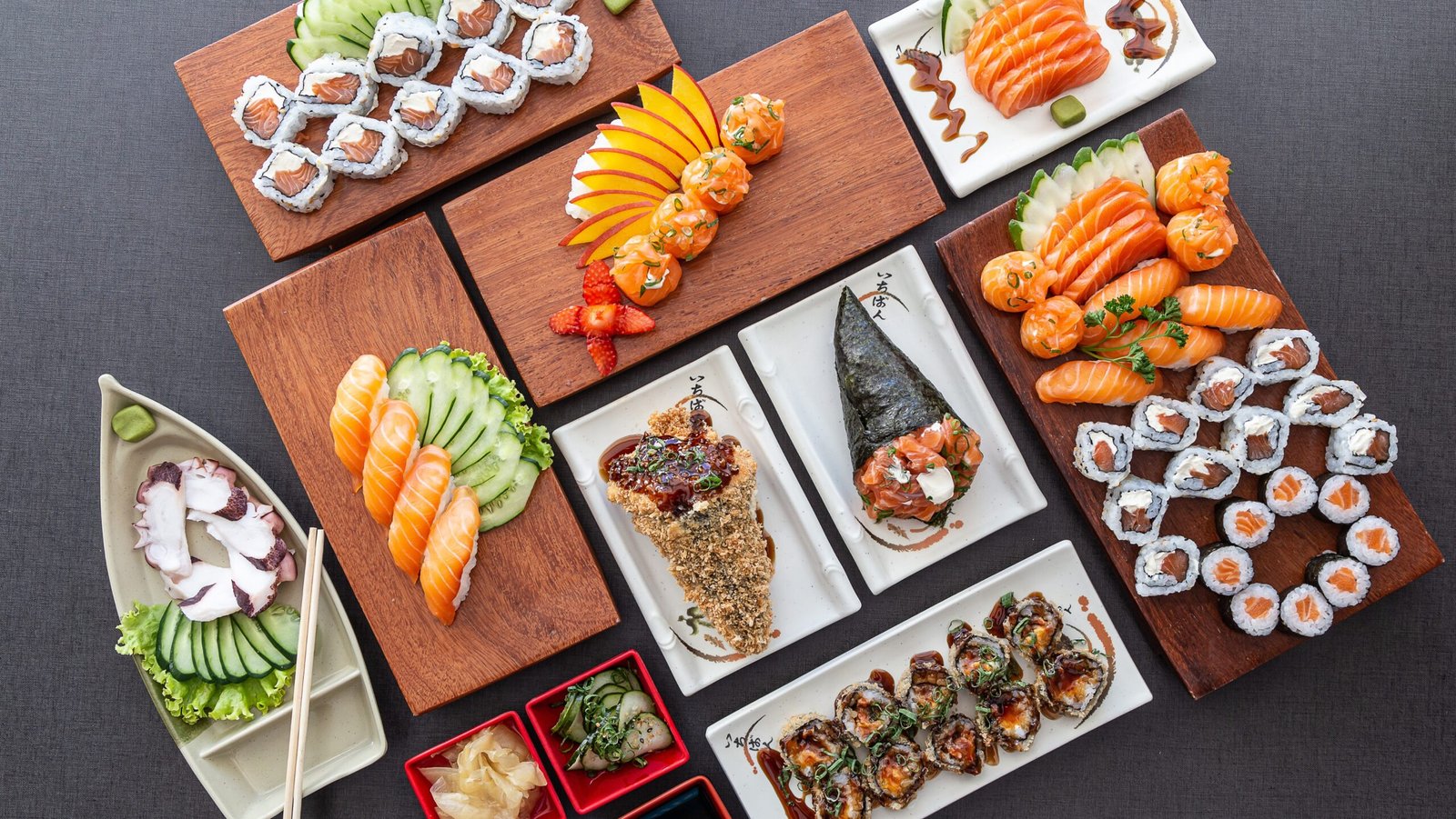 Various Japanese dishes are placed on wooden boards