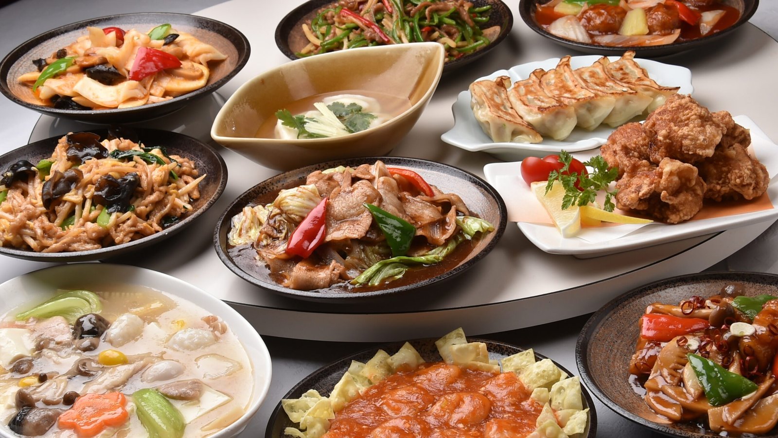 Assorted Chinese dishes are placed on a large table