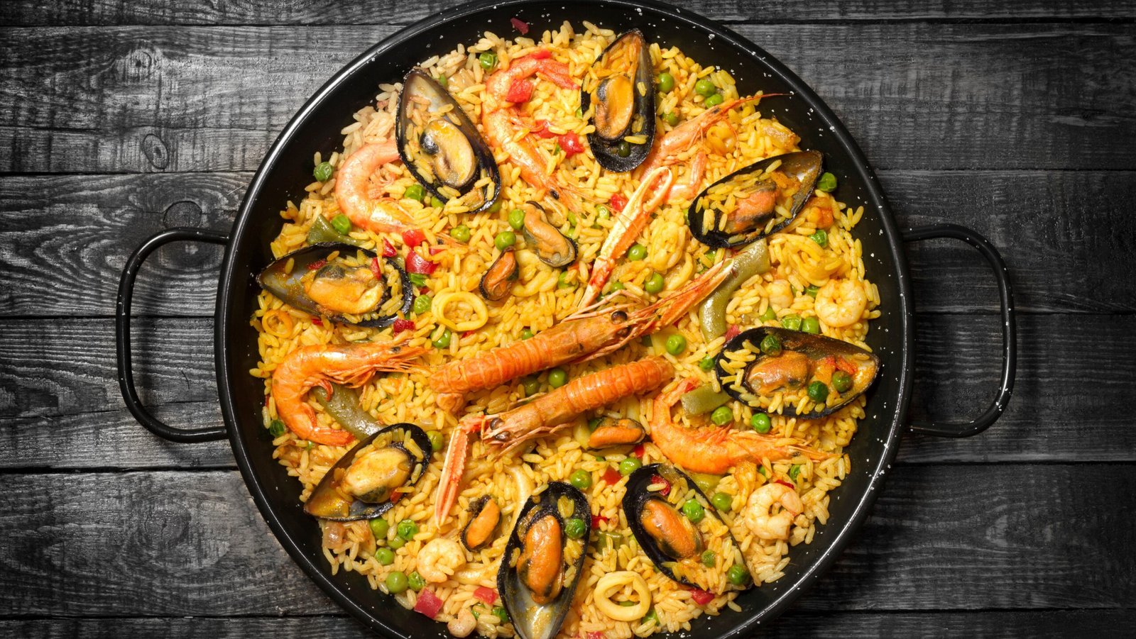 Spanish paella in a pan on a wooden table top view