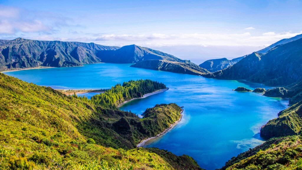 Lush green crater lake in the Azores, Portugal, surrounded by volcanic hills and cloudy skies