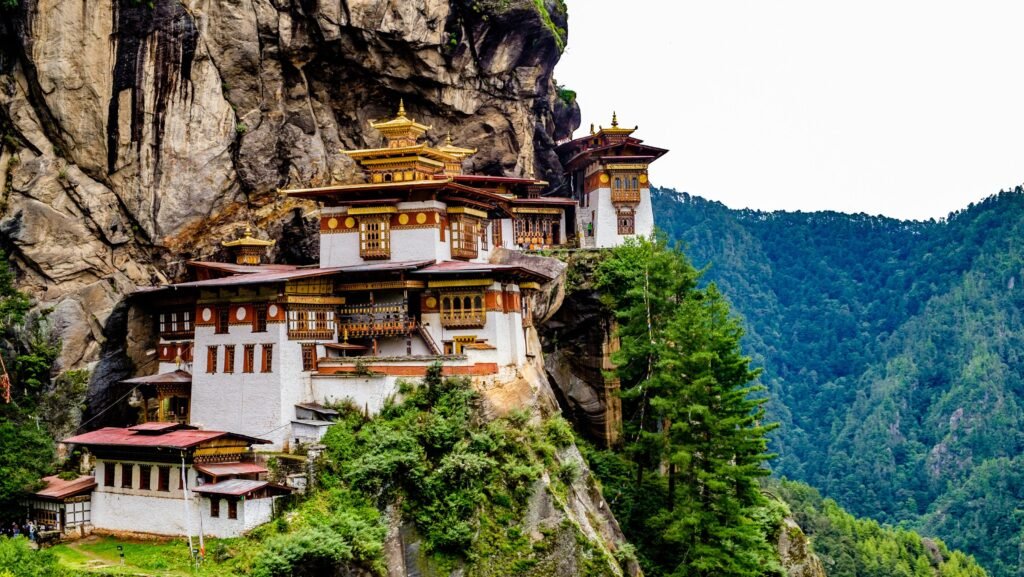 Tiger's Nest Monastery perched on a cliff in Bhutan, surrounded by lush mountains and misty skies.